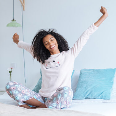 Happy woman sat on bed