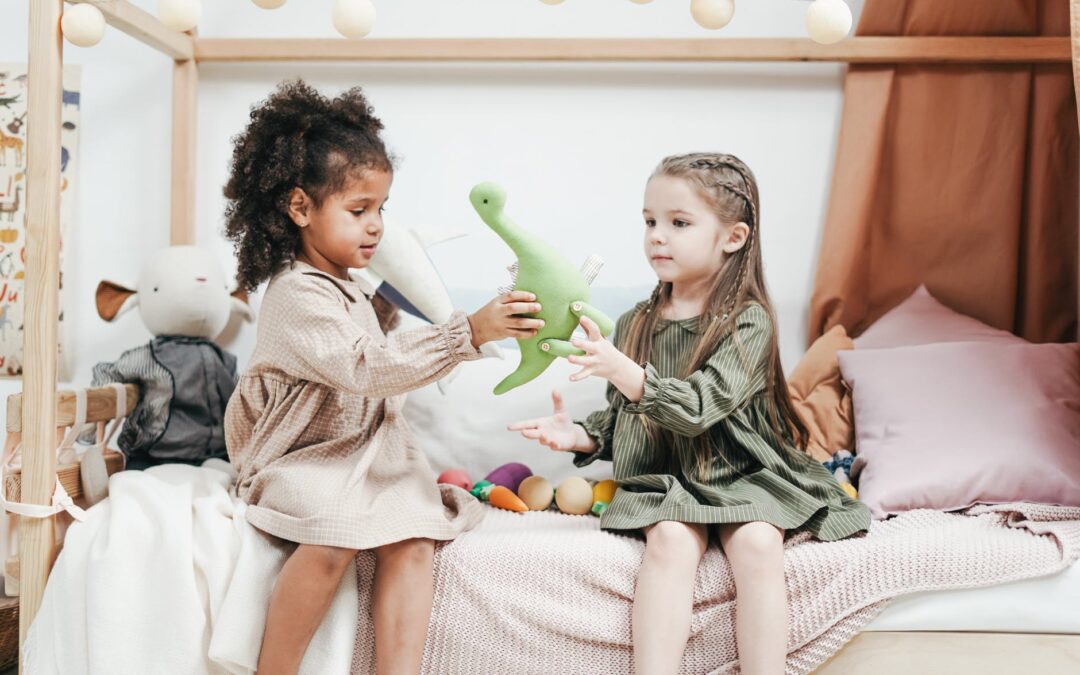 Two children sitting on a bed playing with a toy dinosaur.