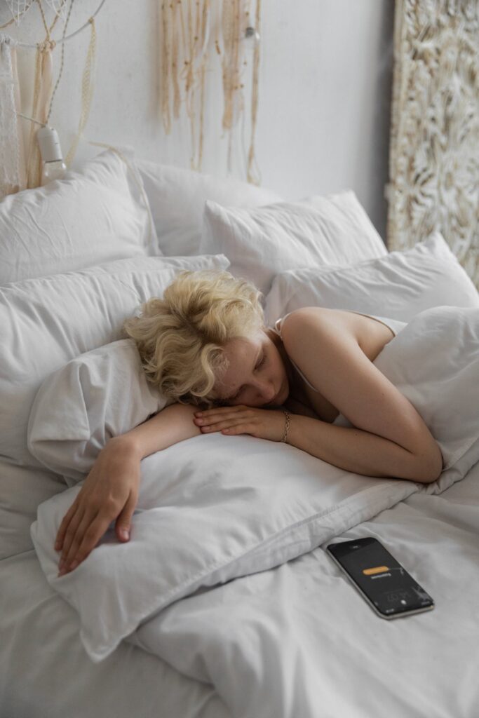 Blonde woman falling to sleep quickly with her phone on her bed