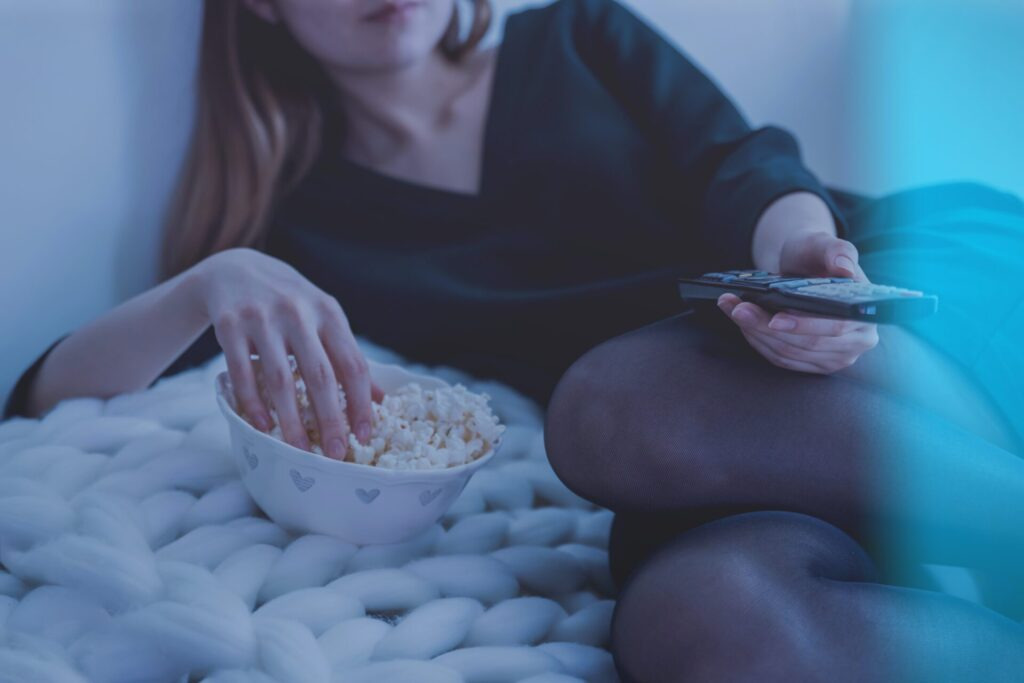 Lady eating popcorn on her bed